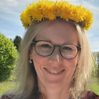 Porträt Melli mit einem Blumenkranz im Haar aus gelben Löwenzahnblüten