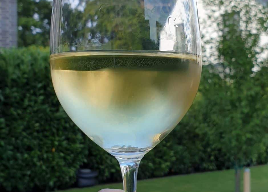 Glas Wein in einer erhobenen Hand als Symbol für das Hochleben lassen