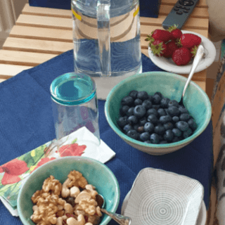 Blauberren, Nüsse, Erdbeeren in Schüsseln mit einer Karaffe Wasser auf dem Tisch