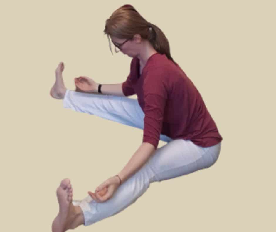 Vorwärtsbeuge, eine Yoga-Haltung. Frau sitzt mit gegrätschten Beinen auf dem Boden und beugt sich mit gerade Rücken nach vorn